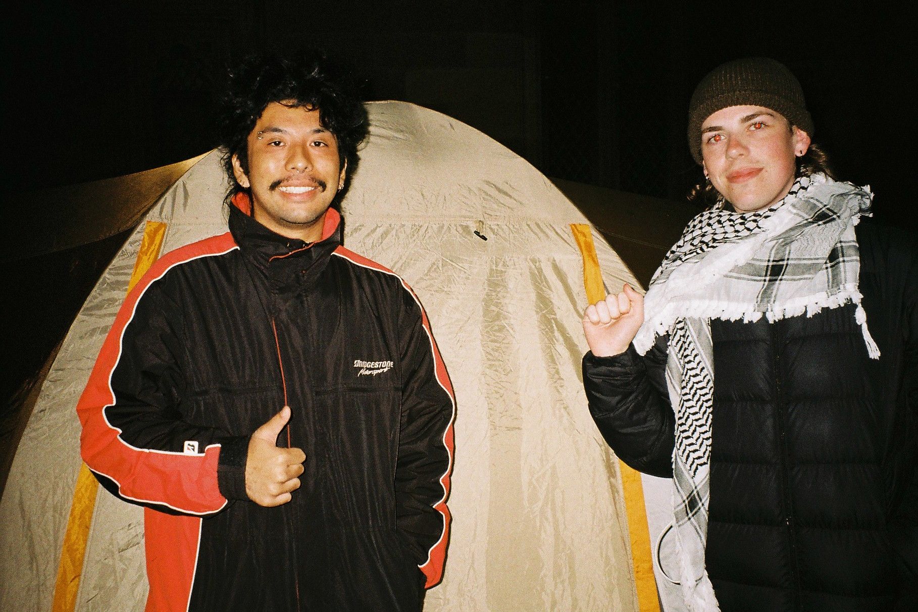 Two people posing outside a tent